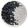A white dish filled with black and clear heart-shaped acrylic decoration beads.