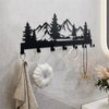 Black metal mountain forest silhouette key holder with hooks mounted on a white wall.