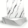 A stack of white marble peel-and-stick wall panels featuring black veining, displayed on a white surface.