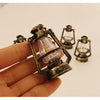 A hand holds a vintage ceramic miniature lantern with a glass bulb and brass fittings for dollhouse décor.