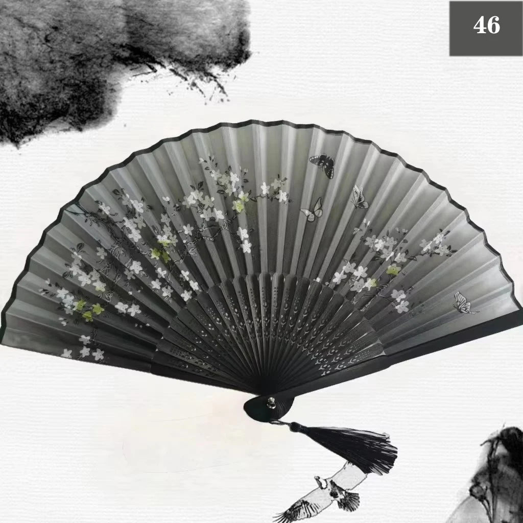 A black vintage silk bamboo folding hand fan with delicate floral designs and butterflies.