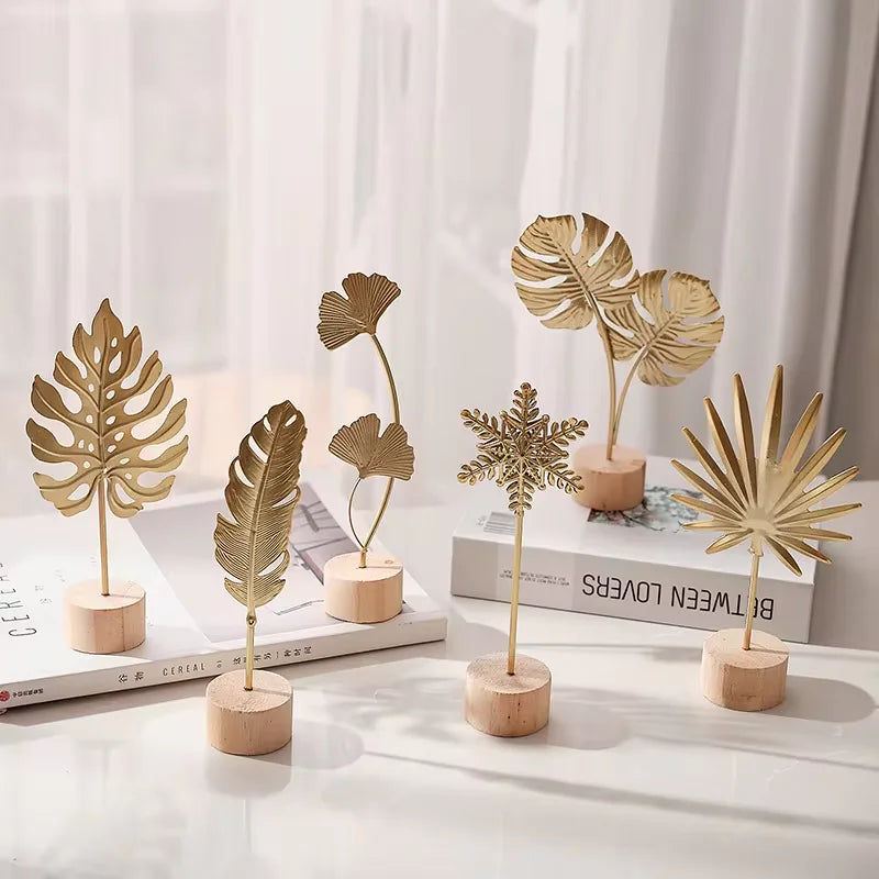 A collection of golden ginkgo leaf metal decorative sculptures displayed on a white surface.