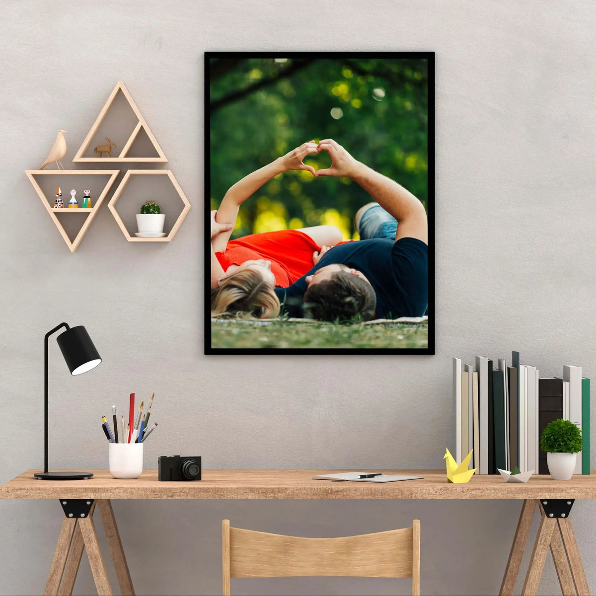 A framed photo of a couple holding hands, resting their heads on each other outdoors, displayed on a gray wall above a wooden