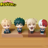 Four chibi collectible figures of My Hero Academia characters including Izuku, Bakugo, Shoto, and Toga displayed on a wooden 