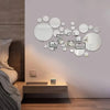 A wall decor set featuring various circular 3D acrylic mirrors mounted on a light gray wall above a wooden shelf.