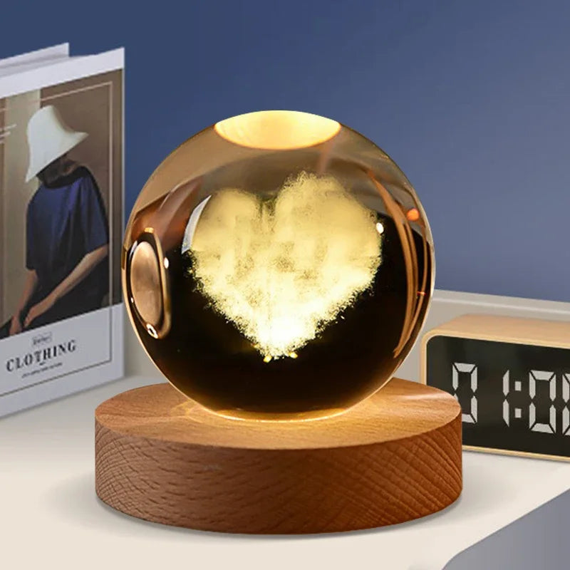 A dark glass crystal ball with a heart shape etched inside, resting on a wooden base.