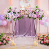 Vases de centre de table en acrylique élégants avec des fleurs roses et violettes sur une table drapée violette.