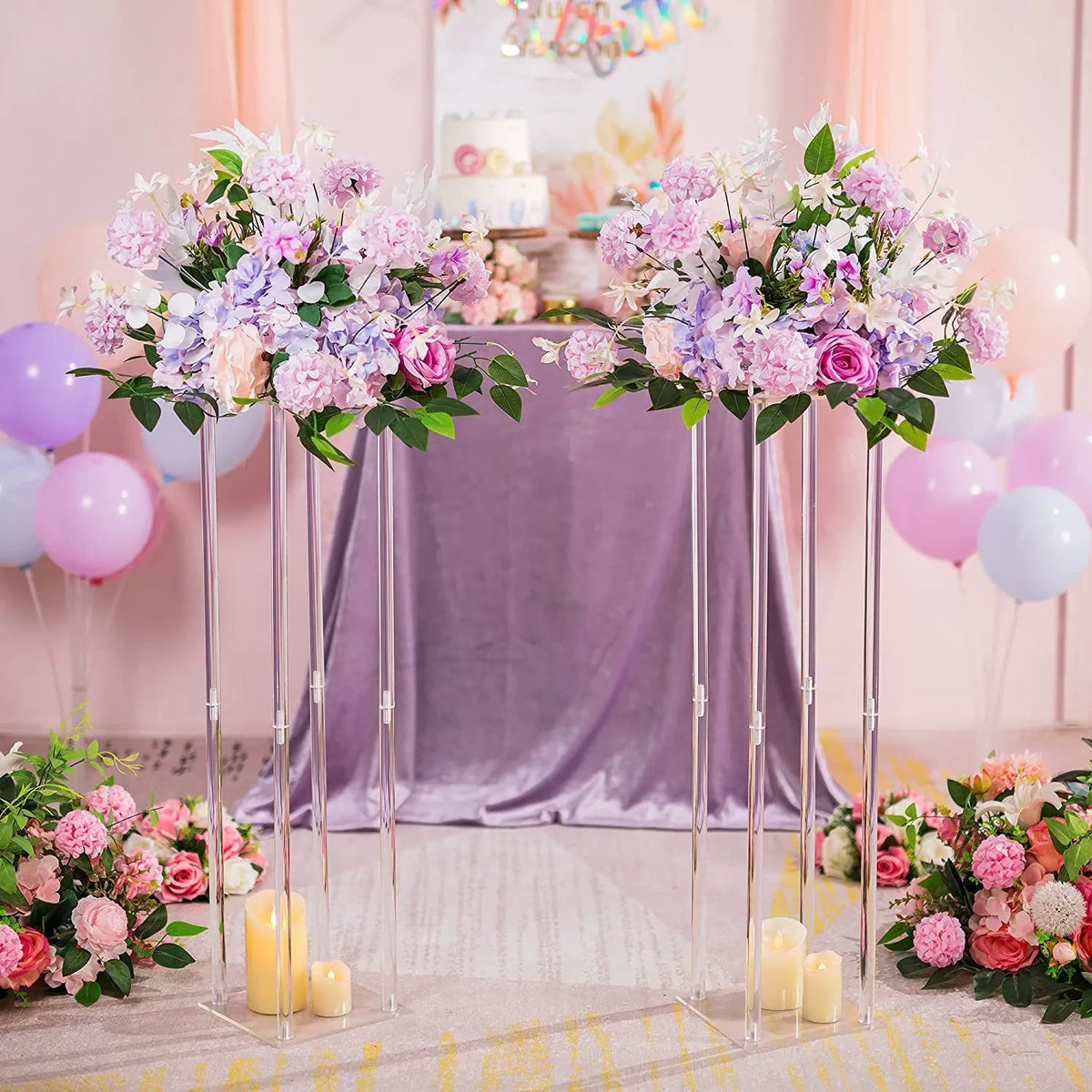 Vases de centre de table en acrylique élégants avec des fleurs roses et violettes sur une table drapée violette.