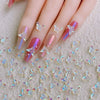 Primer plano de uñas decoradas con charms de mariposa brillantes sobre un fondo claro.