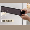 A hand holds a black magnetic spice rack designed for the refrigerator, demonstrating its strength.