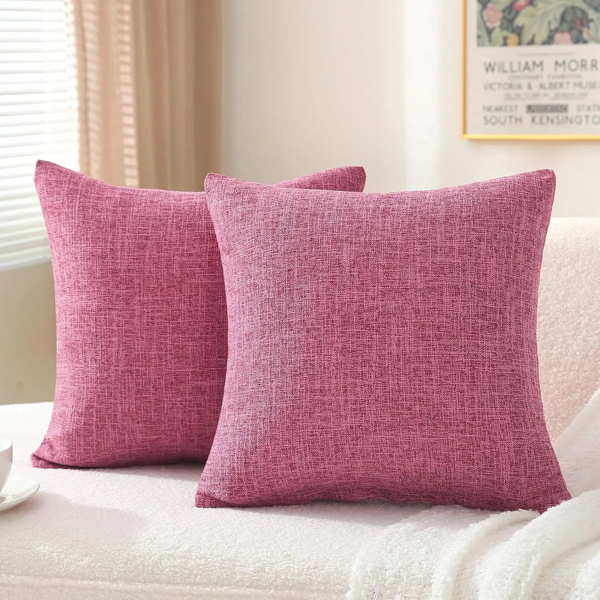 Two solid pink linen pillows resting on a white textured surface.