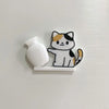 A white acrylic cat whiskered decor and a white bottle are mounted on a silver magnetic strip.
