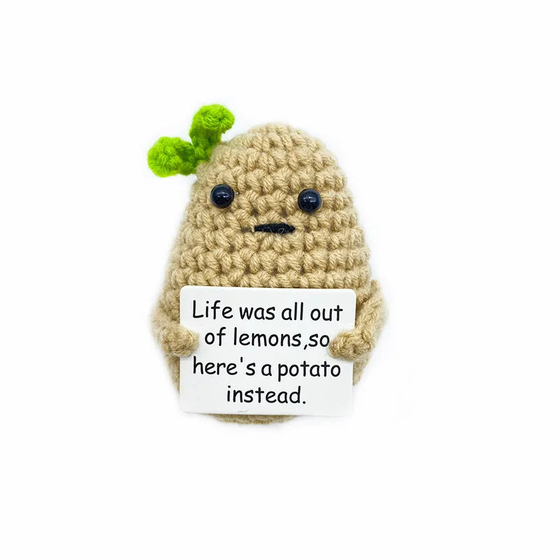 A handmade knitted plush doll resembling a potato with green leaves, holding a sign that reads Life was all out of lemons so 