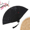 Black vintage bamboo folding fan with subtle gray patterns and a woven straw mat in the background