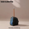 A dark blue crystal resting on a wooden incense stick, used for labradorite aromatherapy.