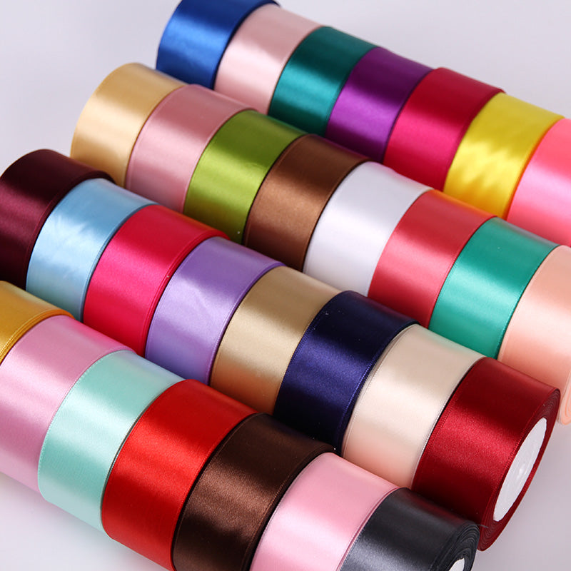 A collection of rolled silk satin ribbons in various colors including pink, green, purple, and red.