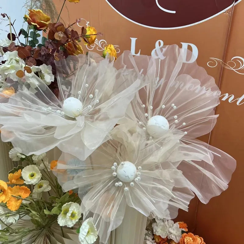 A set of three large, sheer pink and white fabric flowers used as wedding decoration
