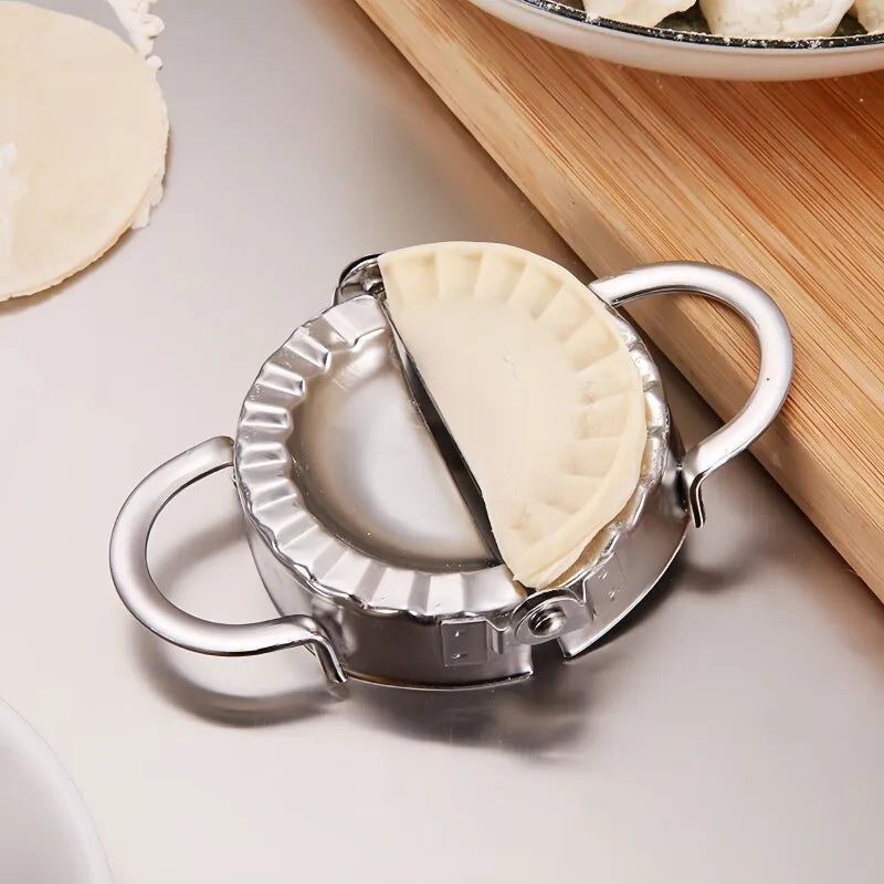 A stainless steel dumpling maker with a crimped edge is shown next to a plate of dough.