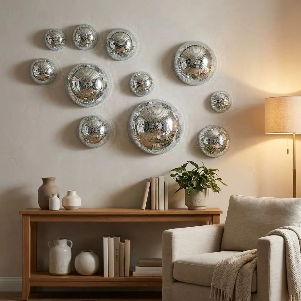 A wall display featuring multiple silver disco balls with adhesive backing mounted on a light-colored wall.