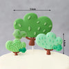 Green clay tree decorations with leaves and branches on a white surface.