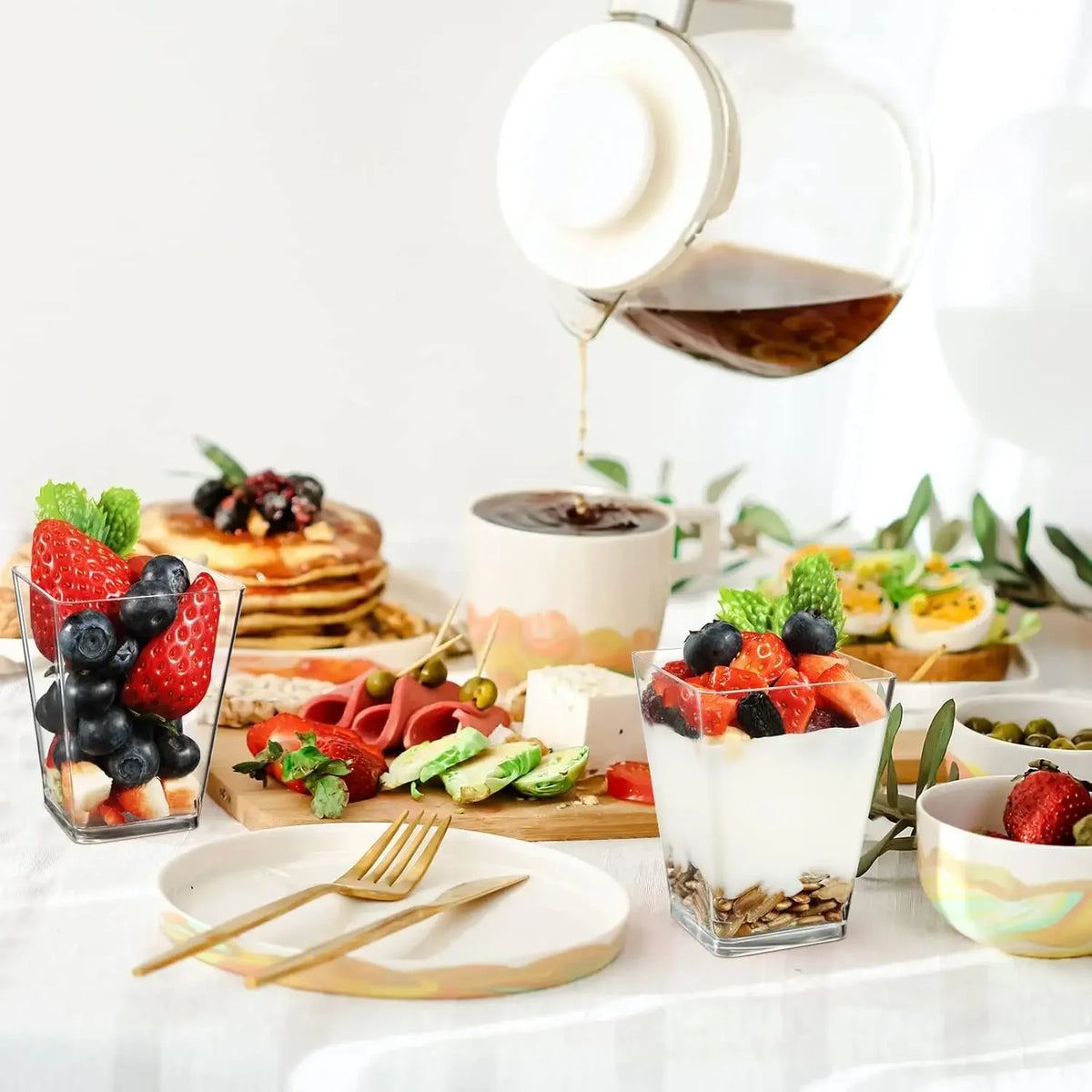A set of six elegant mini dessert cups with spoons filled with layered fruit and cream desserts.