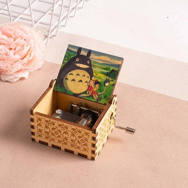 A hand-cranked wooden music box featuring a Totoro design, set against a light background.
