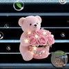 A pink fluffy teddy bear holding a bouquet of pink roses in a glittery pot, displayed on a blue textured surface.