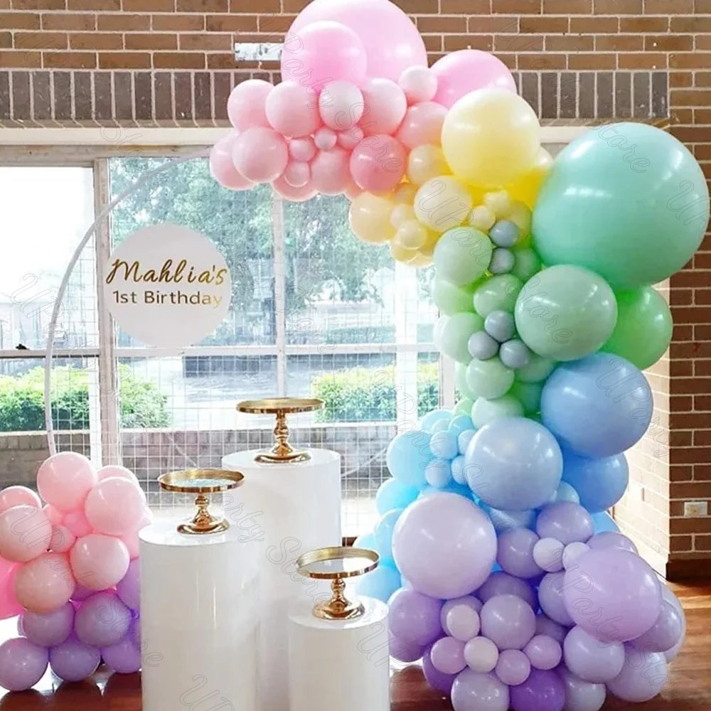 A large arrangement of pastel macaron latex balloons in pink, yellow, and blue clustered together.