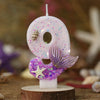 Pink birthday candles shaped like a number eight and a mermaid tail with glitter and starfish decorations