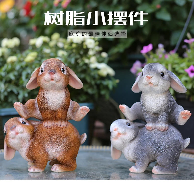 A pair of hand-painted resin rabbit garden statues, one brown and one gray, displayed outdoors.