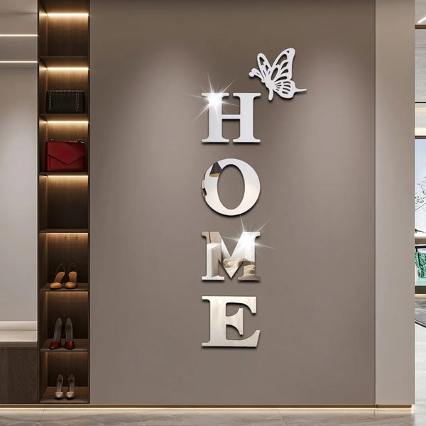 Silver acrylic wall stickers shaped like a butterfly and the word HOME mounted on a light gray wall.