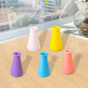 A collection of colorful miniature resin vases in various shades including pink, yellow, purple, and blue on a wooden surface
