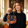 A woman holds up a Halloween acrylic diamond painting kit featuring black cat, moon, skull, and pumpkin designs.