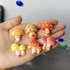 A hand holds a set of nine colorful, cute decorative mushroom fridge magnets.