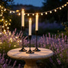 A set of minimalist Nordic round base candle holders with lit white candles displayed on a stone table surrounded by lavender