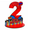 A red wooden number 2 with a spider design and birthday text, featuring cityscape silhouettes.