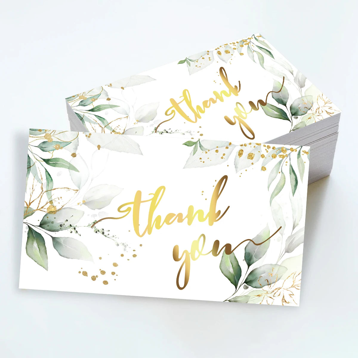 Ein Set eleganter Blumen-Dankeschönkarten mit Gold-Kalligrafie und Aquarellgrün auf weißem Papier.