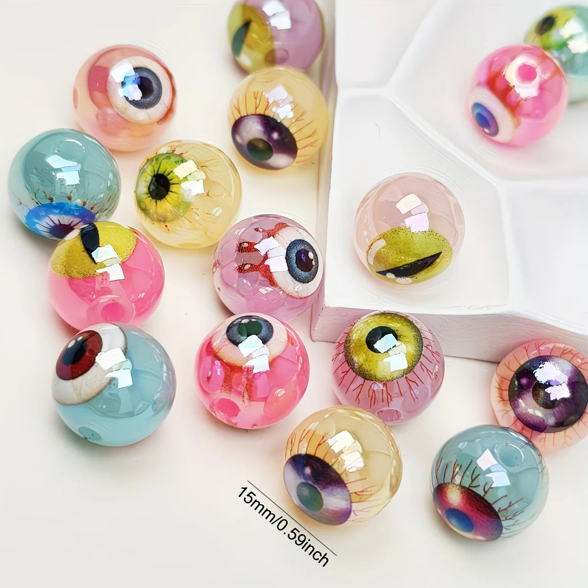 A collection of glossy double-sided eyeball beads in various pink, green, and blue shades for crafting.
