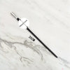 A black metal magic wand replica with a silver tip and a circular label marked Metal Core lying on a white marble surface.