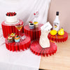 A set of five red decorative acrylic riser stands displaying cakes, a bottle of Malibu, and glassware.