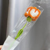 Handmade crochet tulip bouquet featuring orange and white flowers with a green stem inside clear packaging