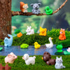 A collection of small, colorful animal figurines including a fox, bear, frog, and various mammals arranged in a green garden 