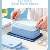 A light blue bento lunch box is shown open, with a hand placing it on a blue cloth next to a fork and spoon.