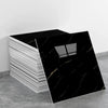 A stack of black marble tile stickers with gold veining displayed on a gray surface.