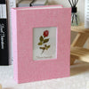 A pink linen cover photo album with a square window displaying a red rose and the text Flower language.