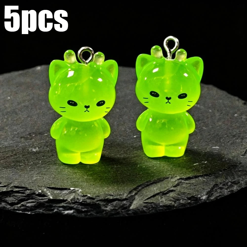 Five glow-in-the-dark green cartoon kitty duck resin charms displayed on a dark surface.