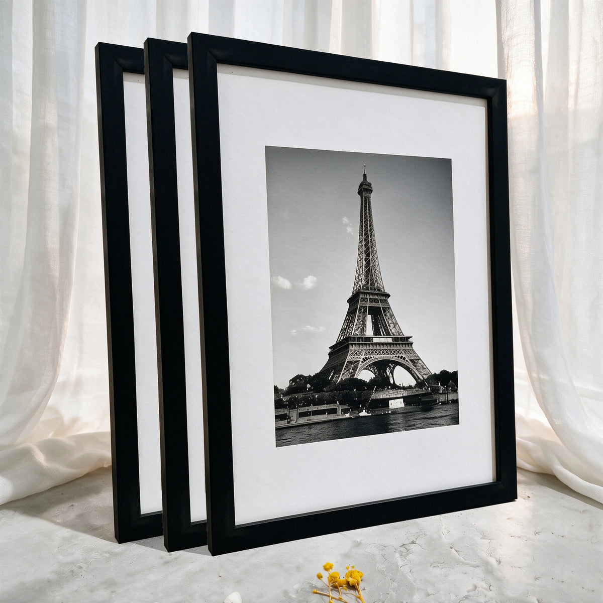A set of three black photo frames displaying a black and white image of the Eiffel Tower.