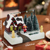 A miniature illuminated Christmas village scene featuring a brick house, Santa, and snowy evergreen trees.