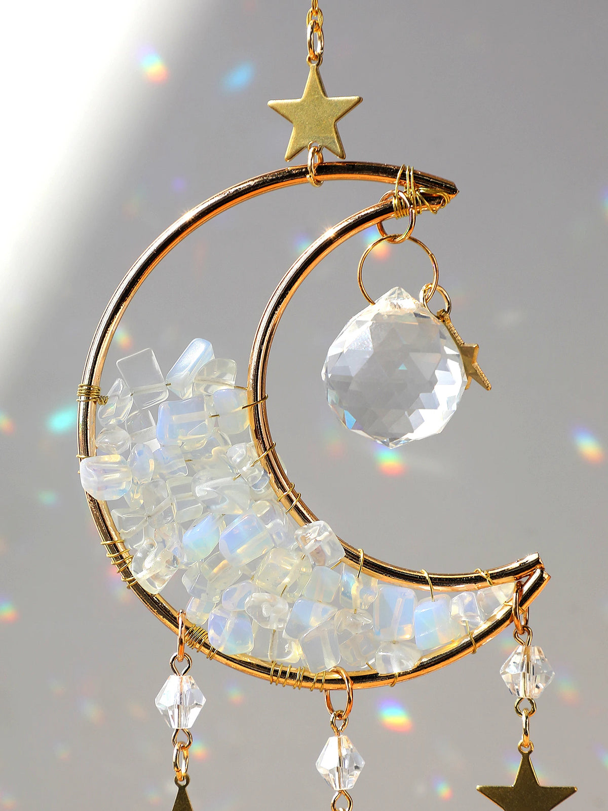 A gold dreamcatcher featuring a crescent moon made of clear quartz crystals and a star charm.