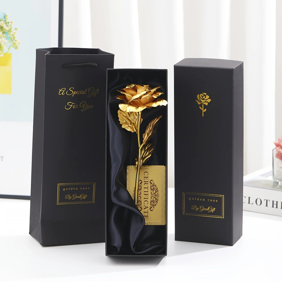 Three black gift boxes with gold foil rose designs and certificates displayed on a white surface.